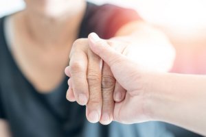 carer hand holding elder hand woman