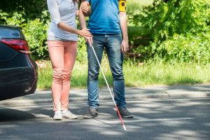 Woman Assisting Blind Man With White Stick On Street