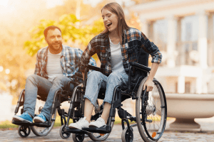 A man and a woman on wheelchairs ride around the park