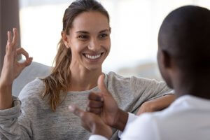 Smiling beautiful woman and African American man speaking sign language